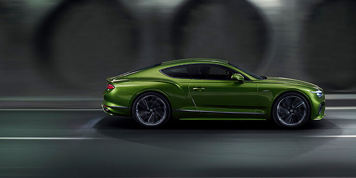  Bentley Manchester Bentley Continental GT coupe in Tourmaline Green paint driving in profile on a dark road