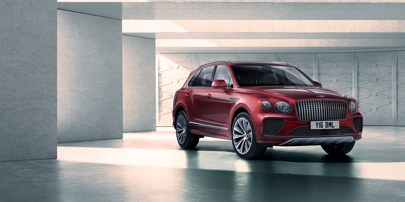 Bentley Manchester Bentley Bentayga Atelier Edition SUV in Rubino Red paint front three quarter against textured concrete wall