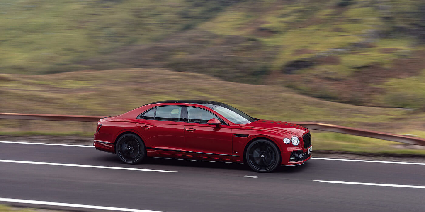 new-Bentley-Flying-Spur-V8-in-Dragon-Red-2-paint-colour-driving-on-mountain-road-in-Scotland-profile-view