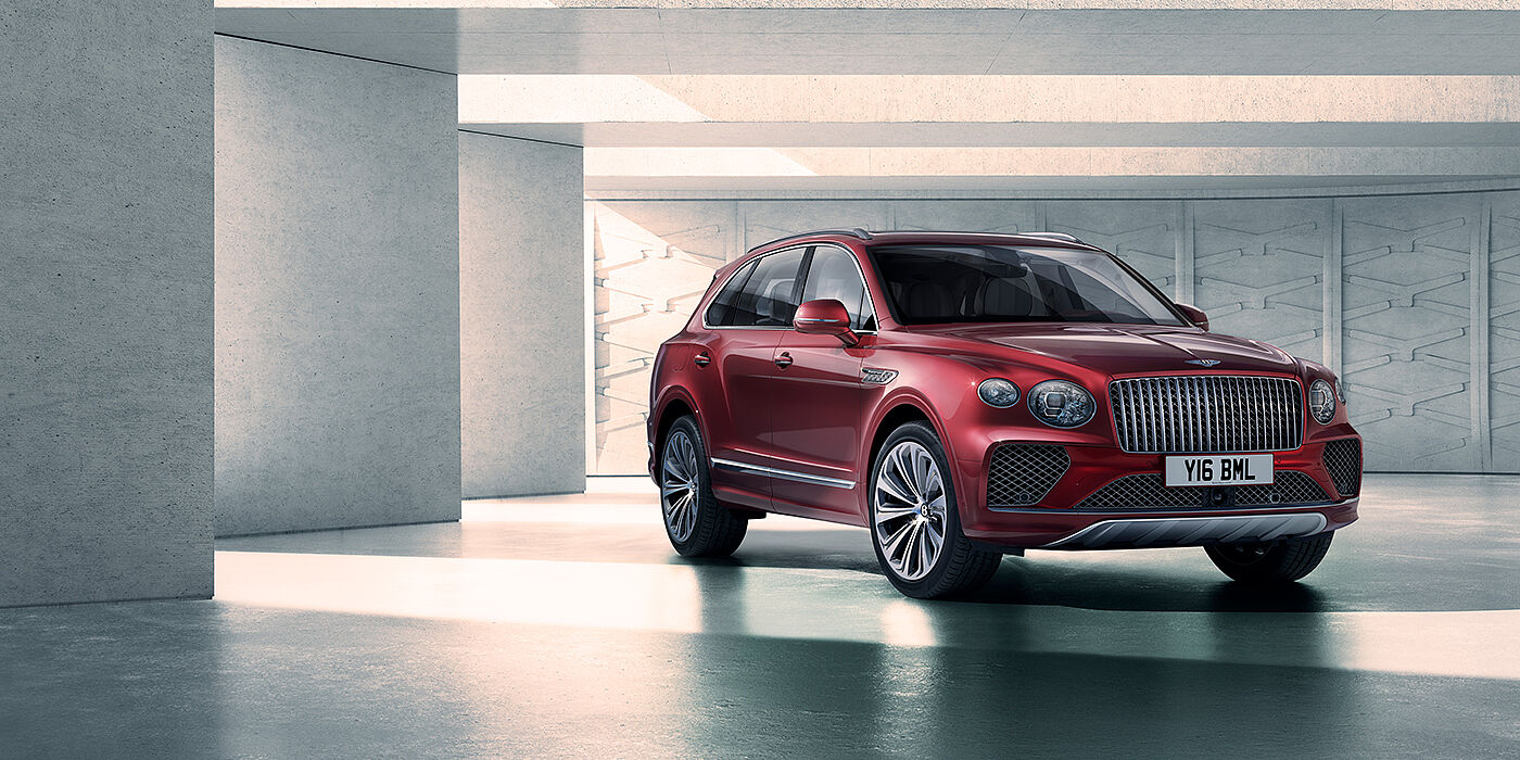 Bentley Manchester Bentley Bentayga Atelier Edition SUV in Rubino Red paint front three quarter against textured concrete wall