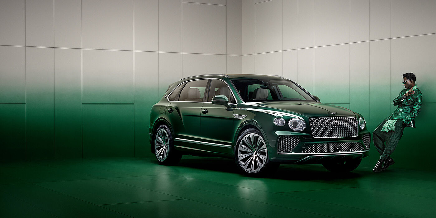 Bentley Manchester Wisdom K leans against wall next to Bentley Bentayga Extended Wheelbase Atelier Edition SUV in Light Emerald green paint