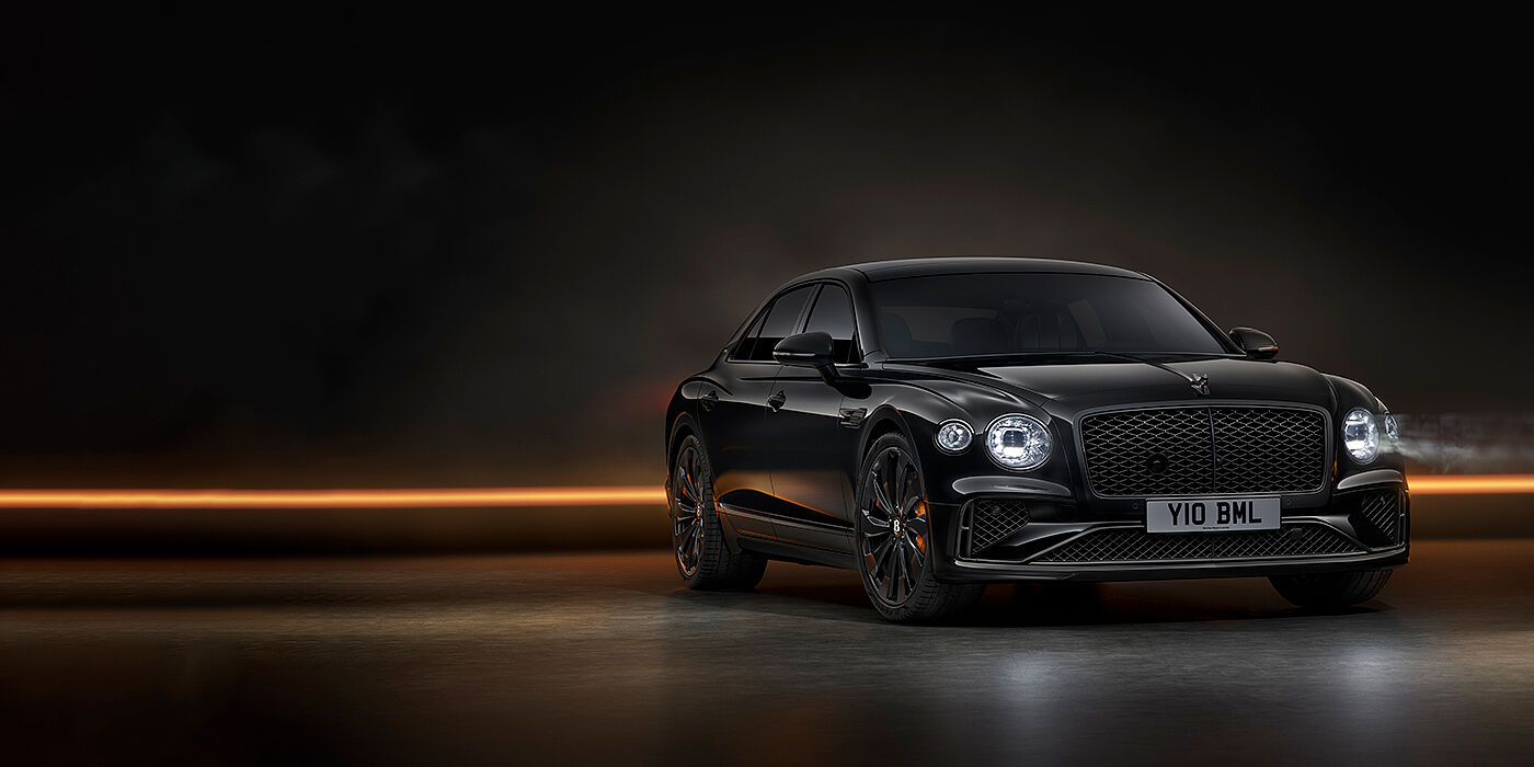 Bentley Manchester Bentley Flying Spur Black Edition sedan in Black Crystal paint against a dark grey and copper coloured background