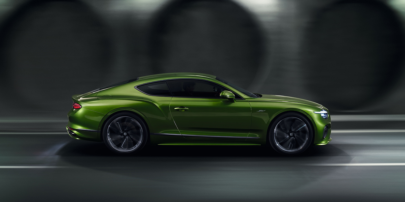 Bentley Manchester Bentley Continental GT coupe in Tourmaline Green paint driving in profile on a dark road